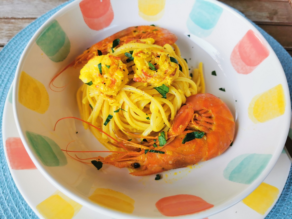 Creamy Italian prawn (shrimp) saffron linguine in white bowl with chopped parsley sprinkled on top.