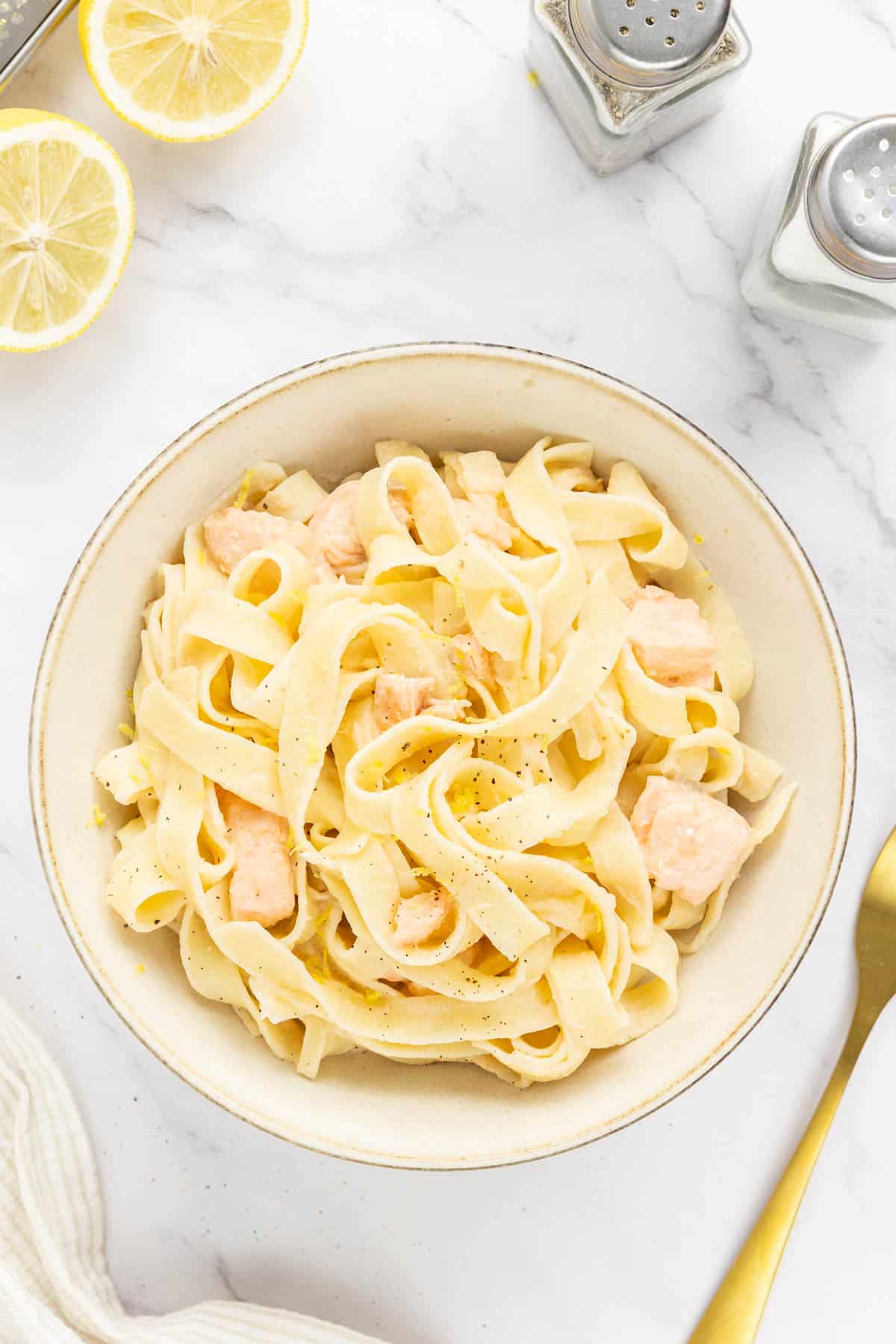 Creamy salmon pasta garnished with lemon zest and pepper.