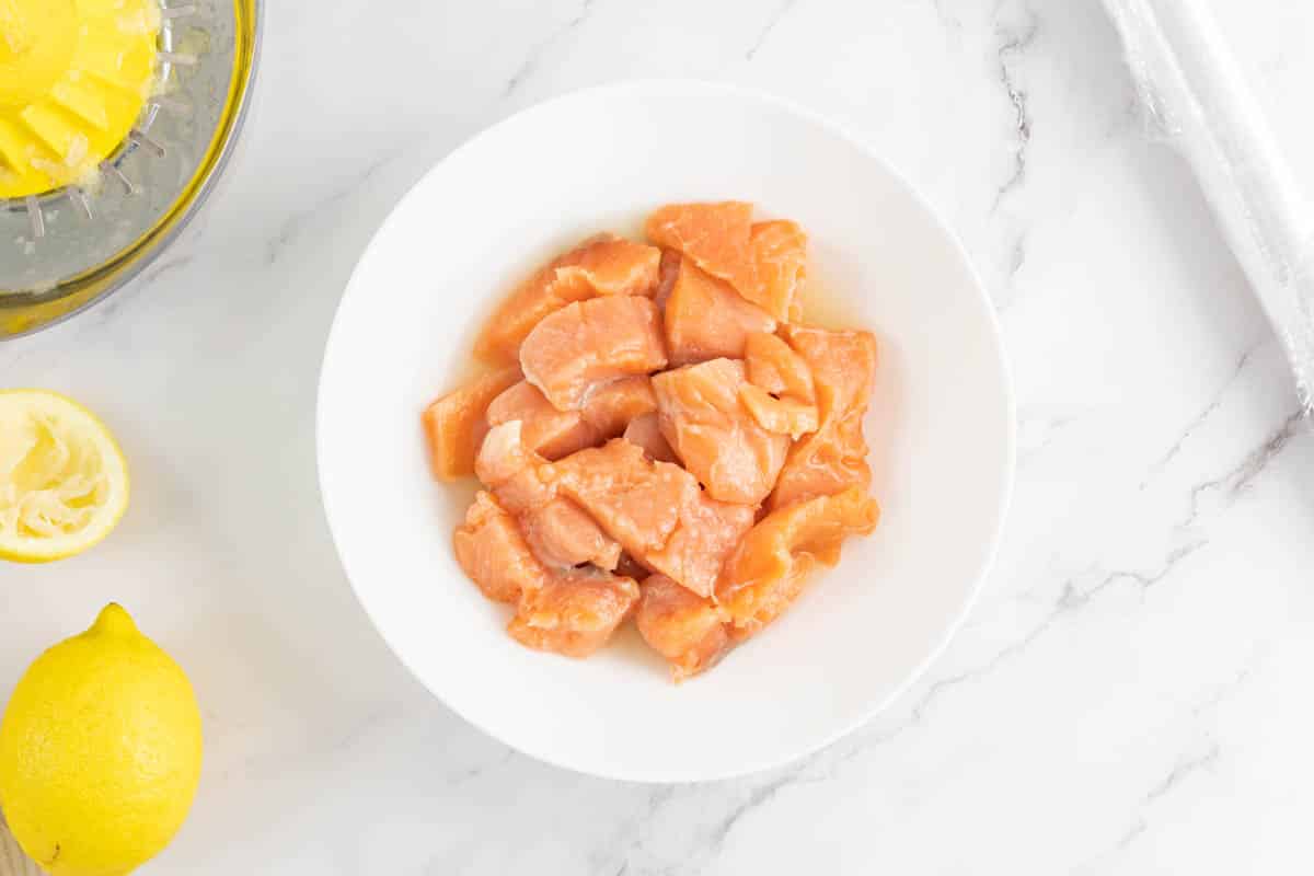 Cubed salmon and lemon juice in a bowl.