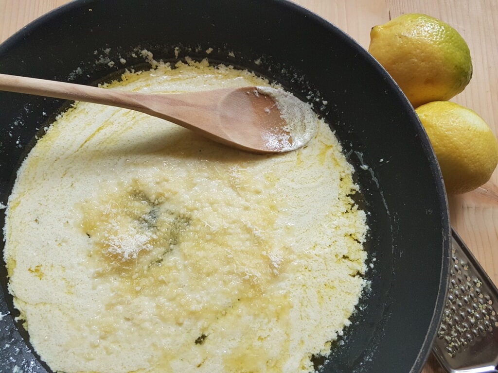 Grated Parmigiano added to skillet with lemon sauce