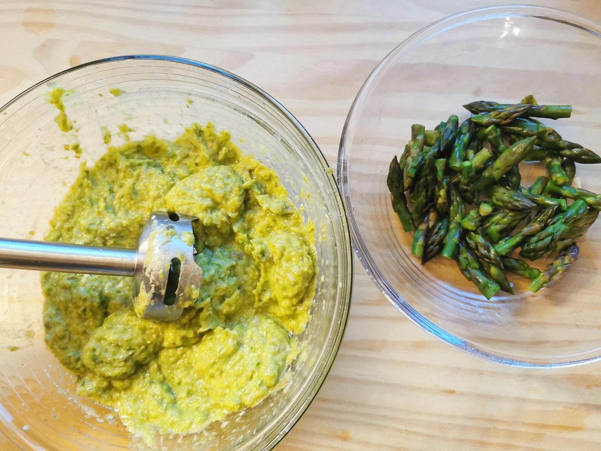 Puréed asparagus and onion in glass bowl and blanched asparagus spears in glass bowl.