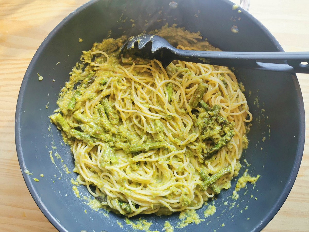 Cooked spaghetti and asparagus sauce tossed together in large skillet.