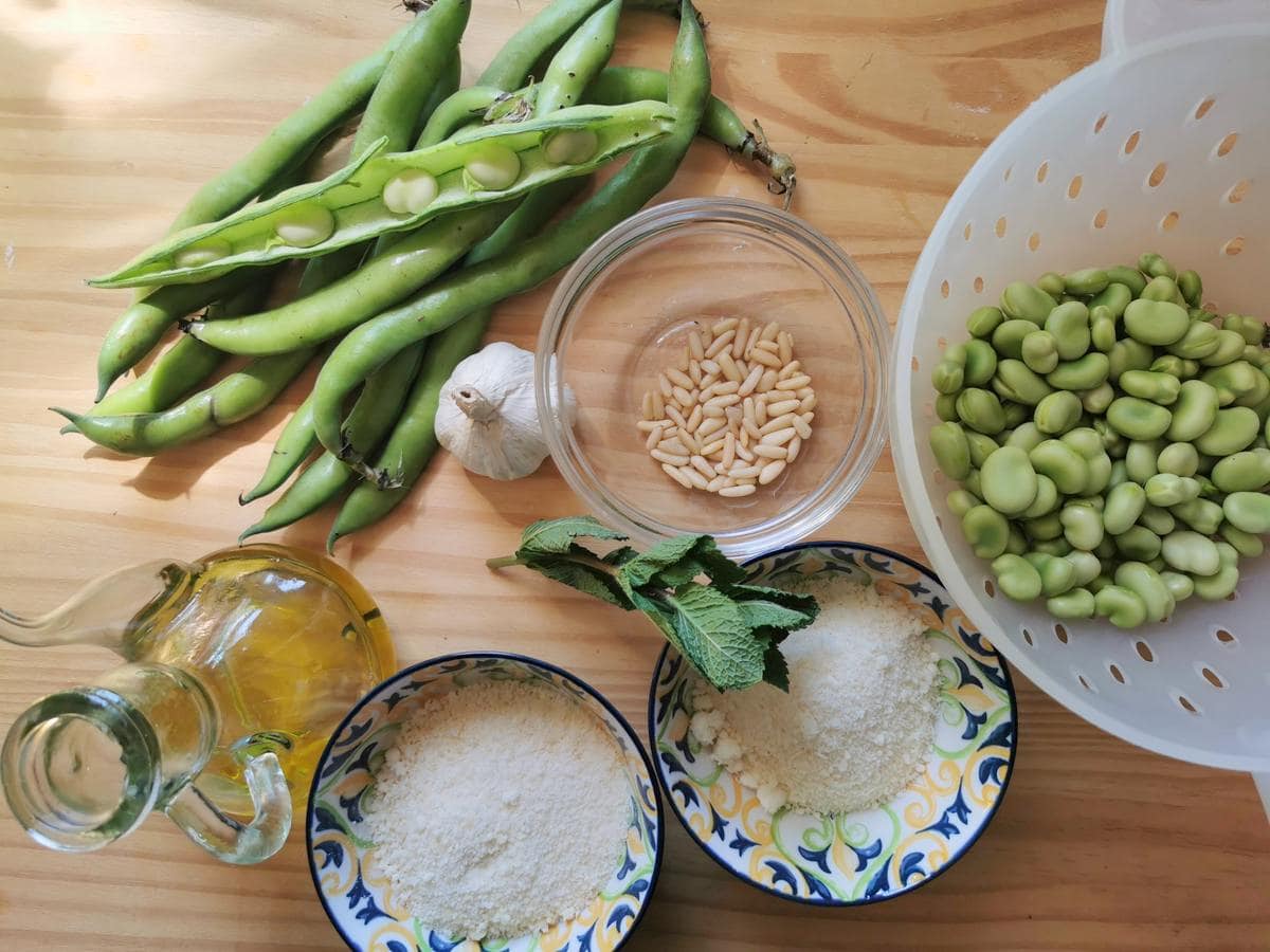 Ingredients for fava bean pesto on wood worktop.