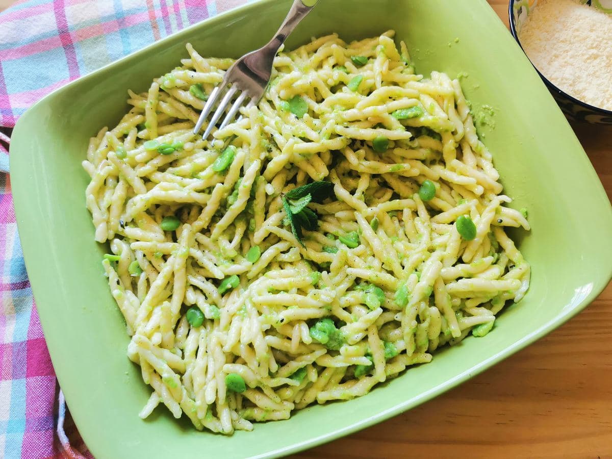 Fava bean pesto with trofie pasta in green ceramic dish.
