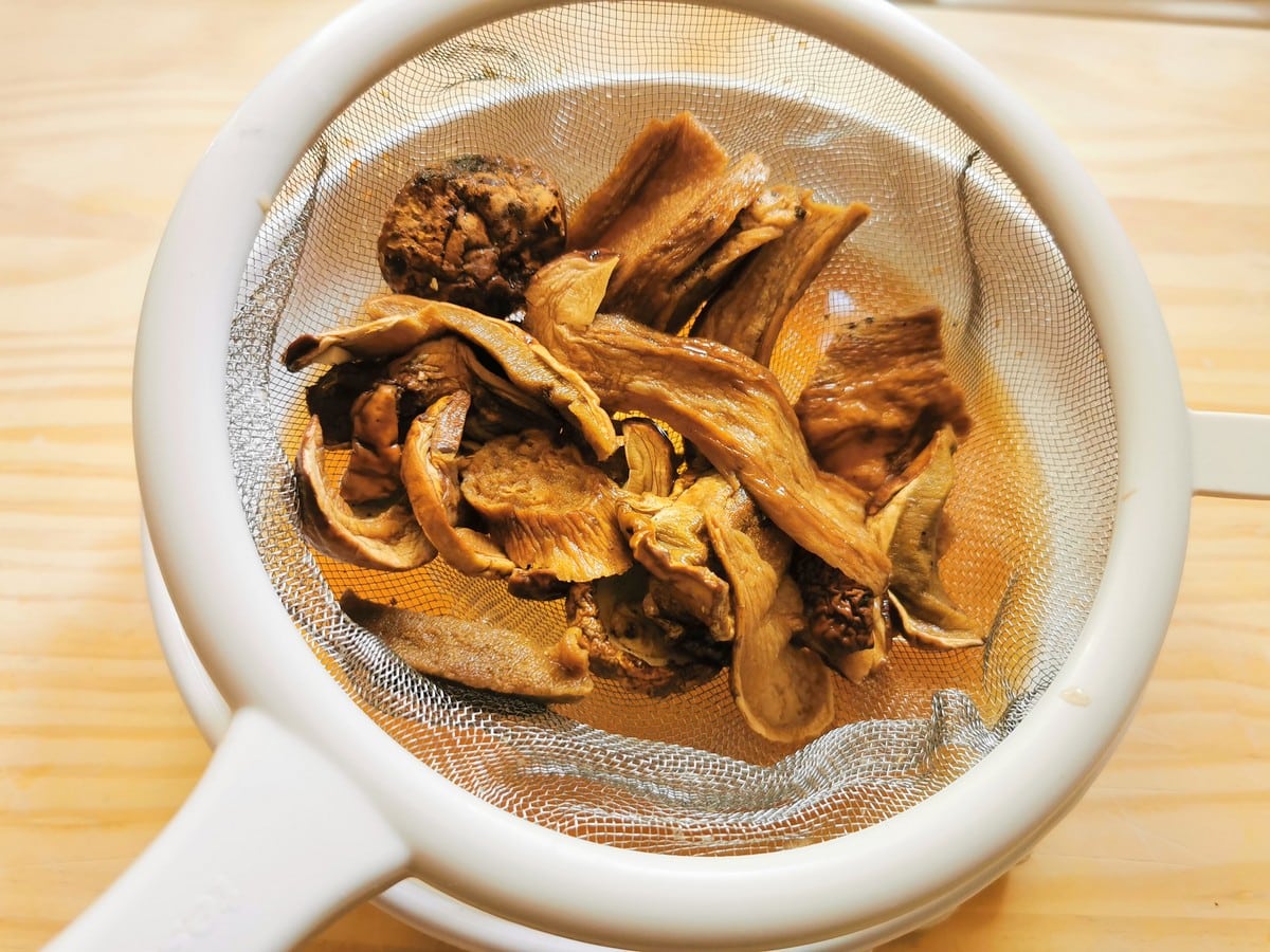 Soaked dried porcini removed from water with a mesh strainer.