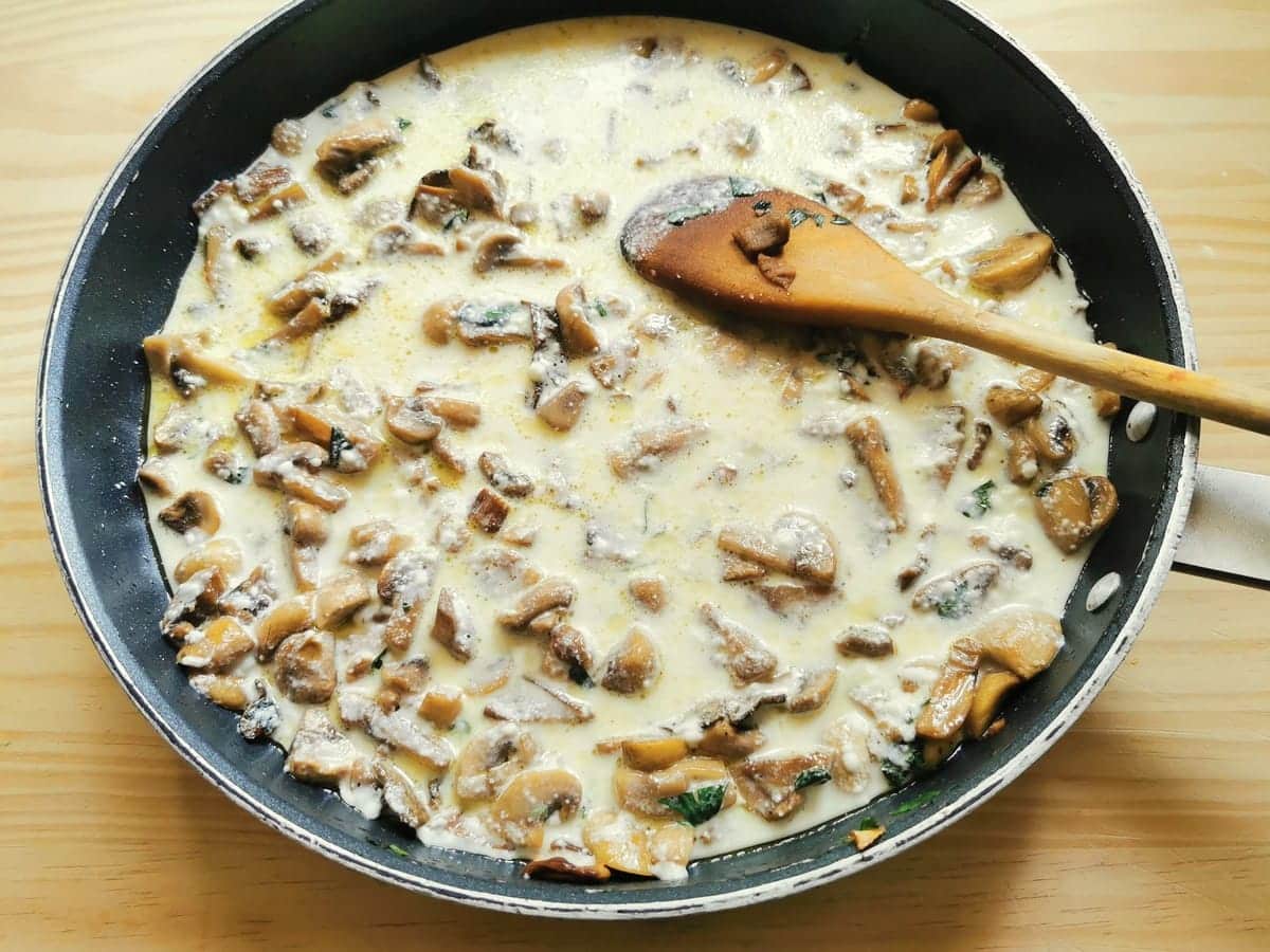 Stracchino sauce added to mushrooms in skillet.