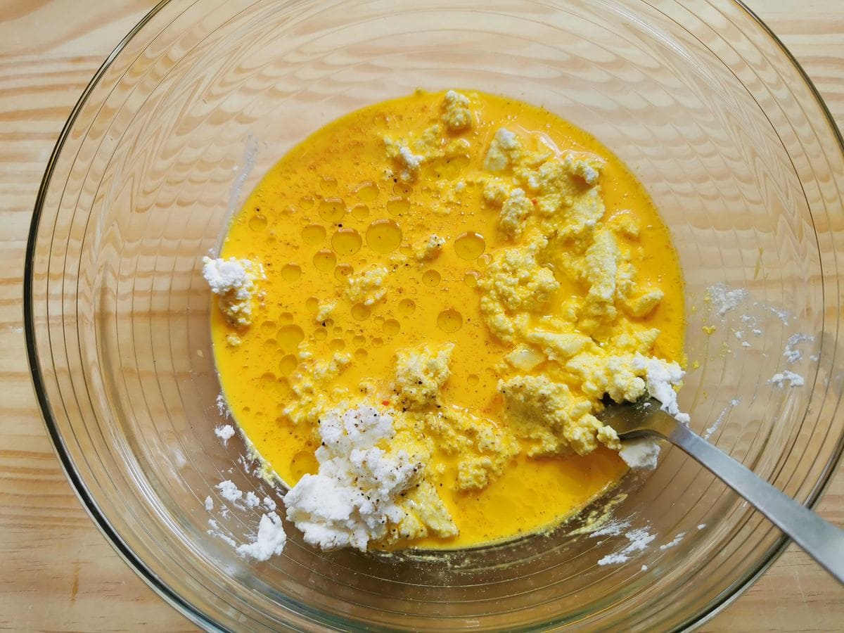 Saffron and milk added to ricotta and olive oil in glass bowl.