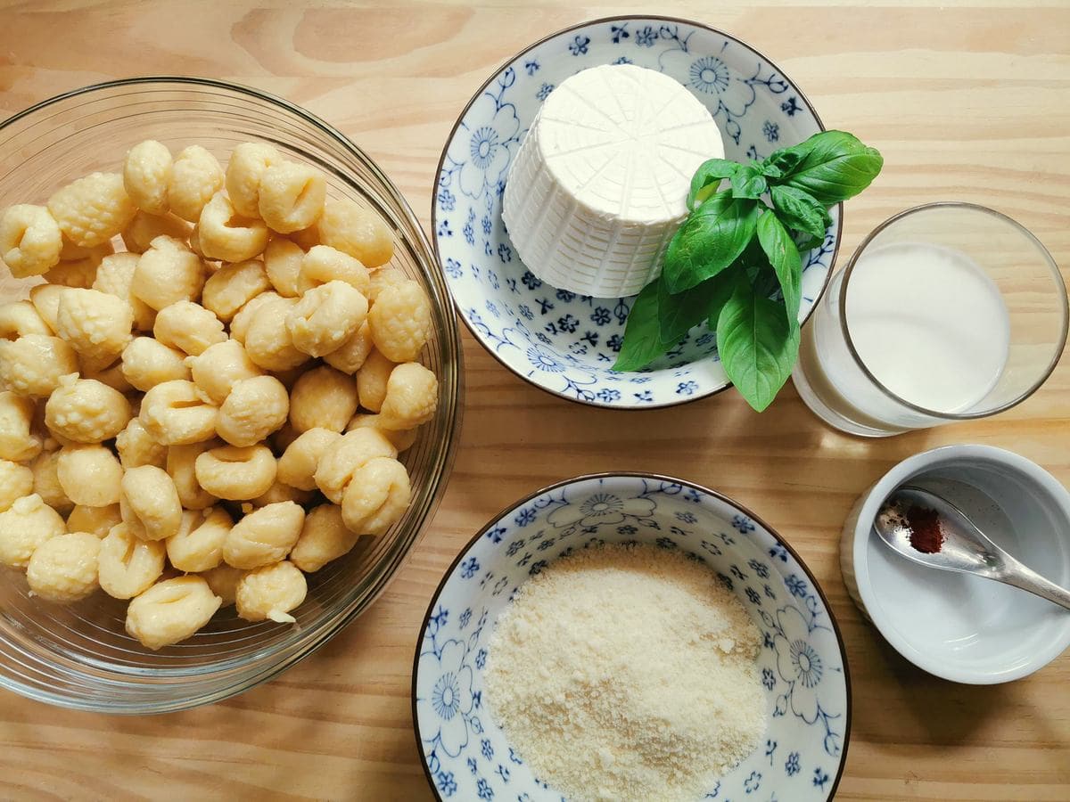 Ingredients for gnocchi with saffron sauce; potato gnocchi, fresh ricotta, basil leaves, milk, saffron powder and grated Parmigiano.