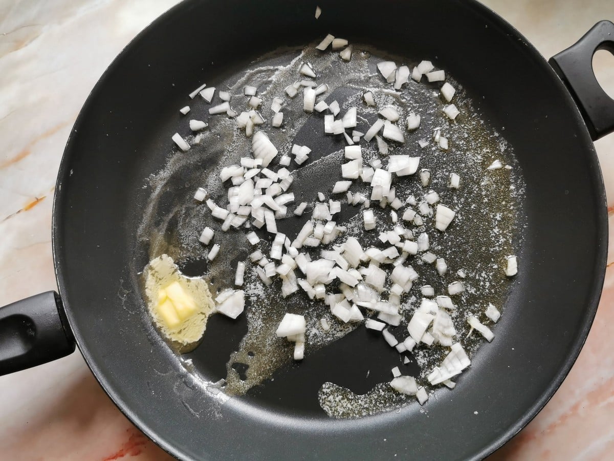 Pieces of onion with melted butter in skillet.