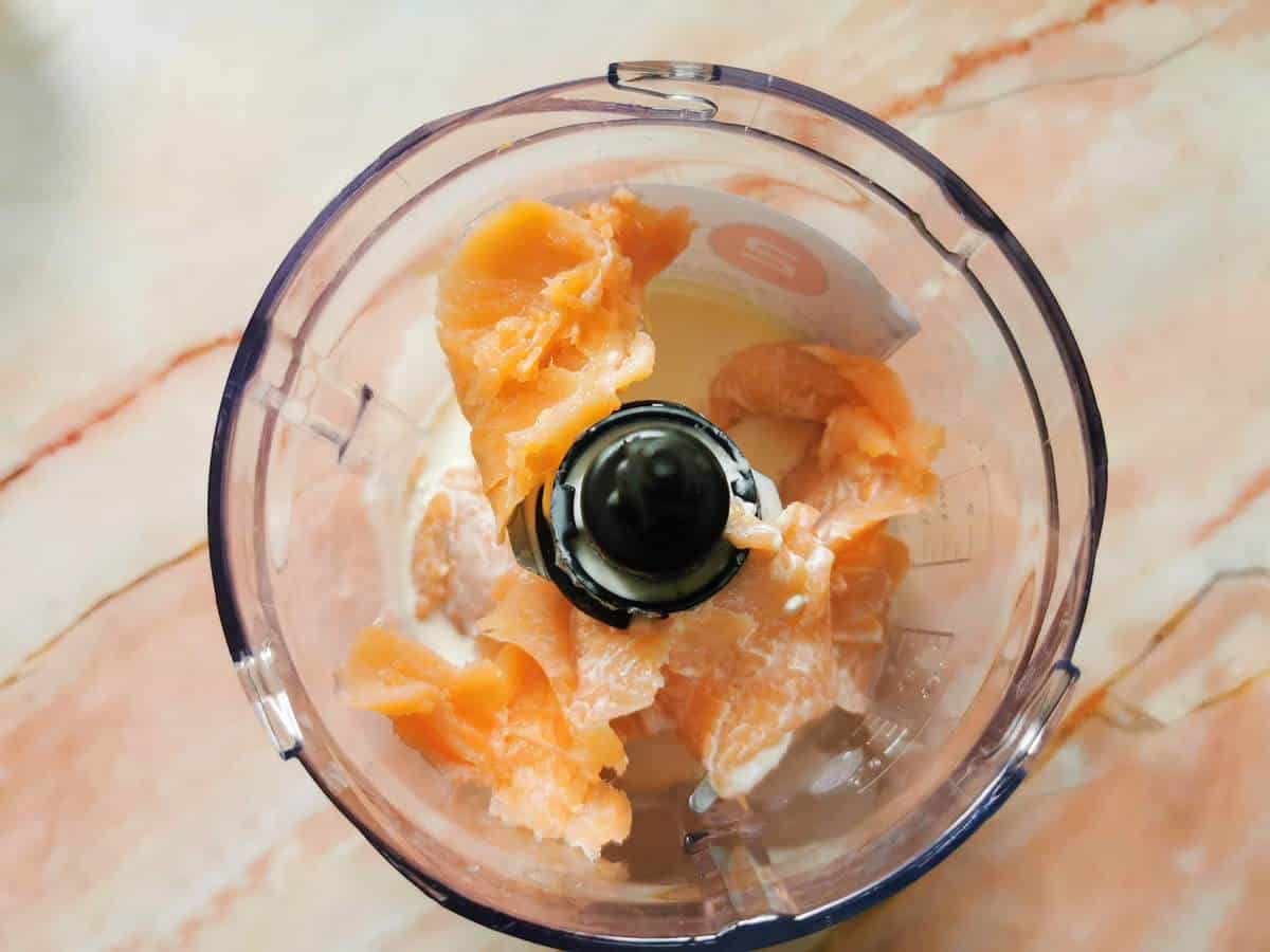 Pieces of smoked salmon and cream in a food processor.