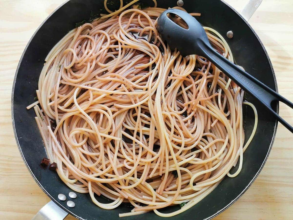 Drunken spaghetti cooking in skillet with red wine.