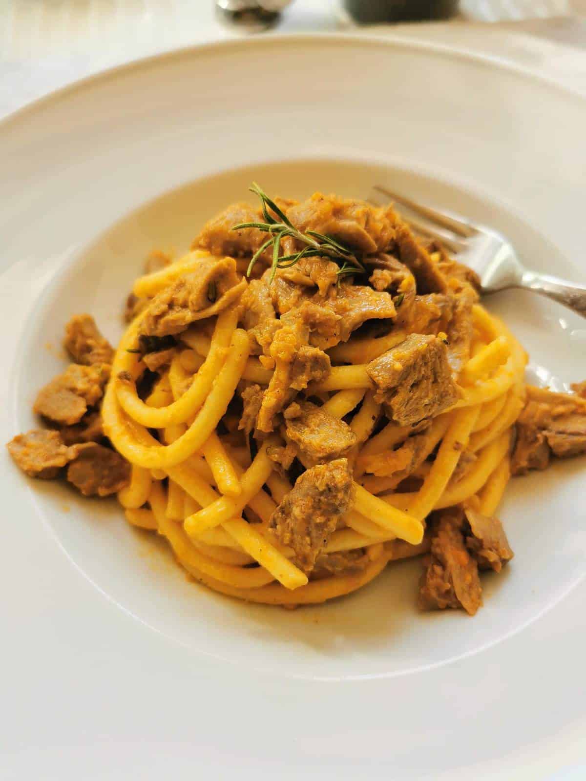 Duck pasta in a bowl with a fork.