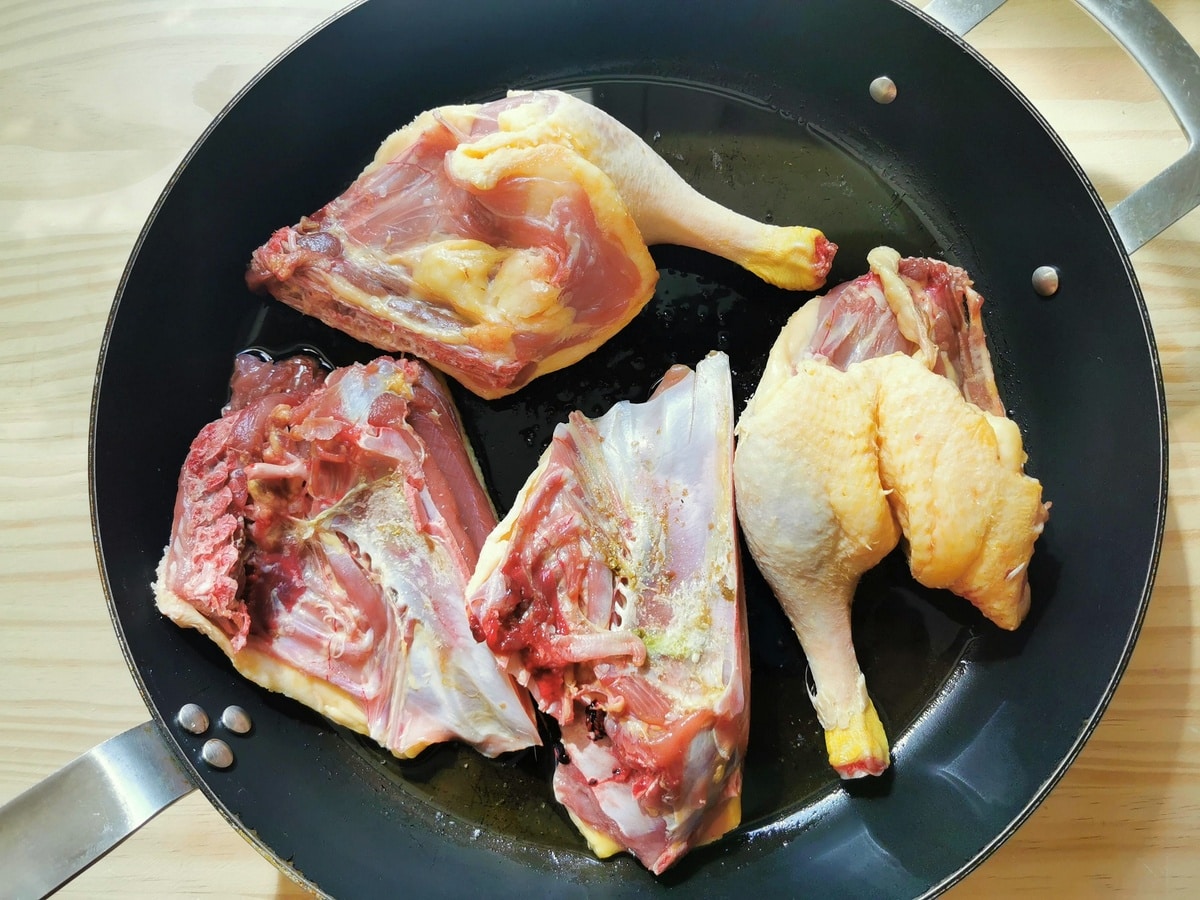 Duck searing in a large sauté pan.