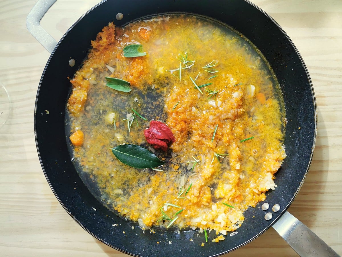 Broth, tomato concentrate, sage, rosemary, and bay leaf added to the pan.