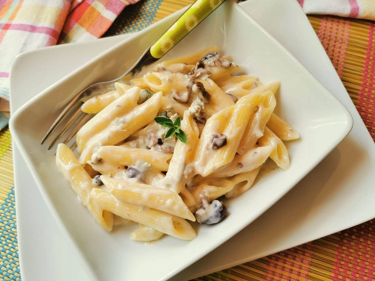 gorgonzola pasta with black olives in white bowl