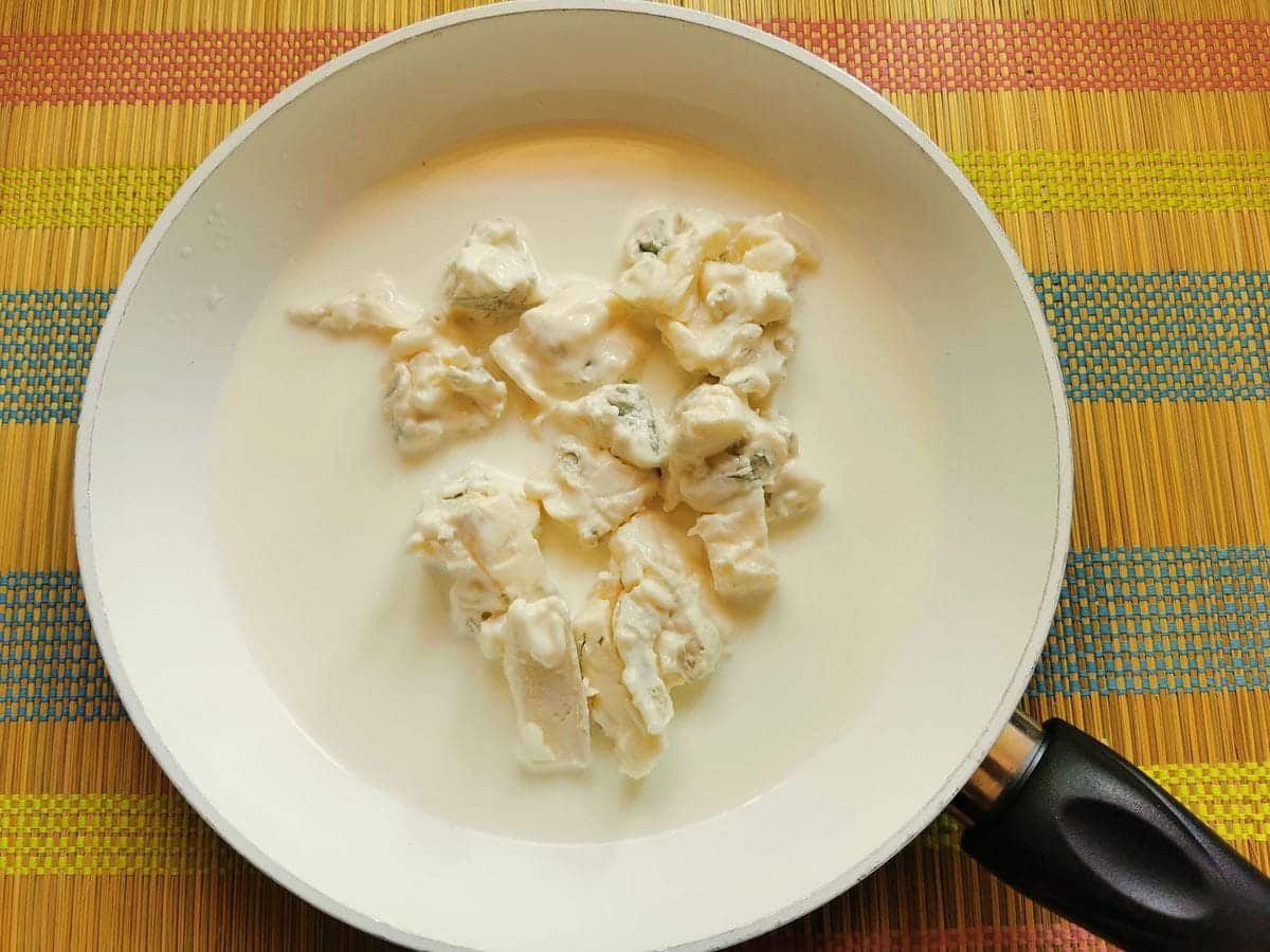 pieces of gorgonzola and milk in white pan