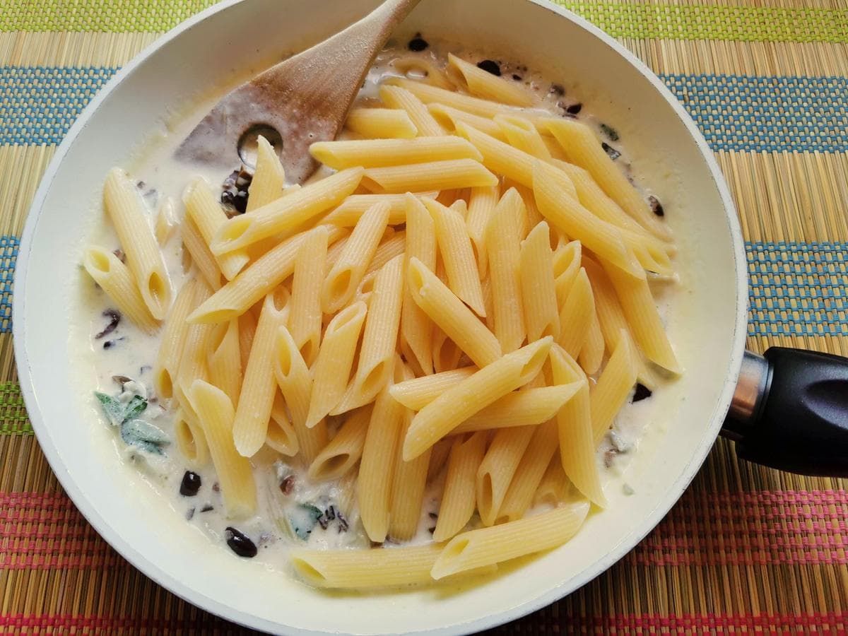 cooked pasta in pan with gorgonzola and olives sauce