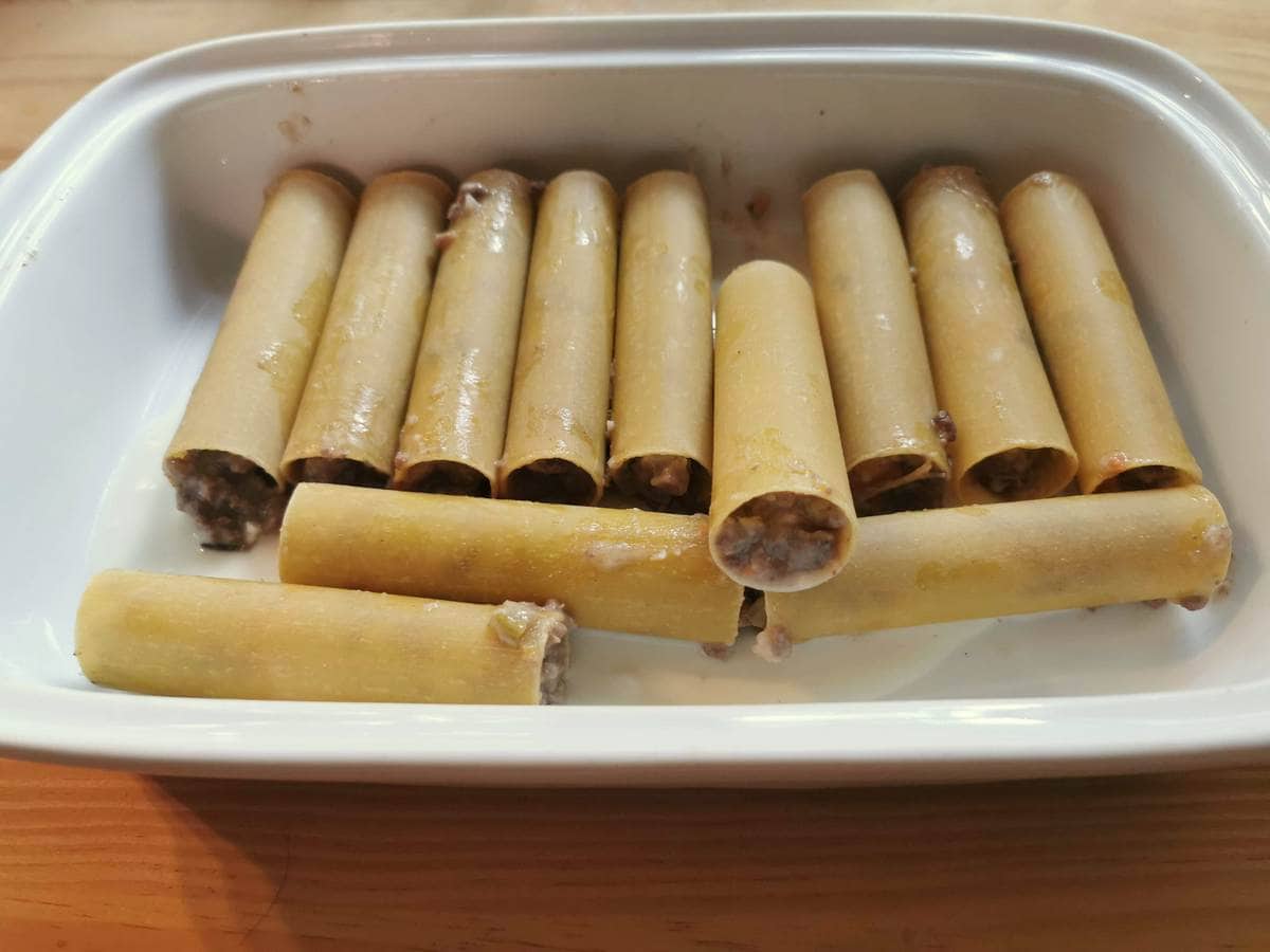 Filled uncooked beef cannelloni in oven dish.