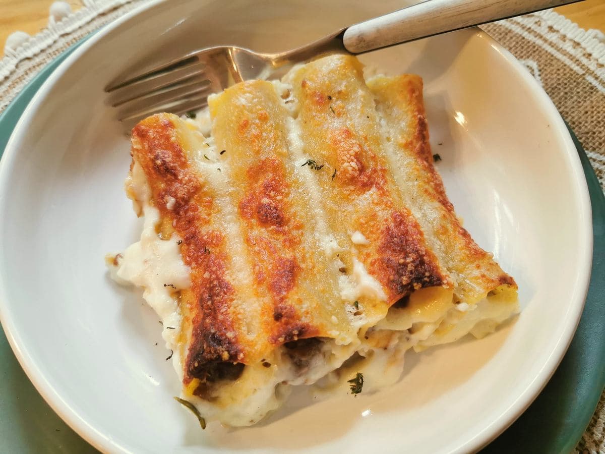 Italian beef cannelloni in white bowl with fork.