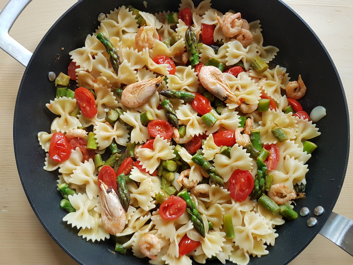 Ready Italian shrimp and asparagus pasta in skillet.