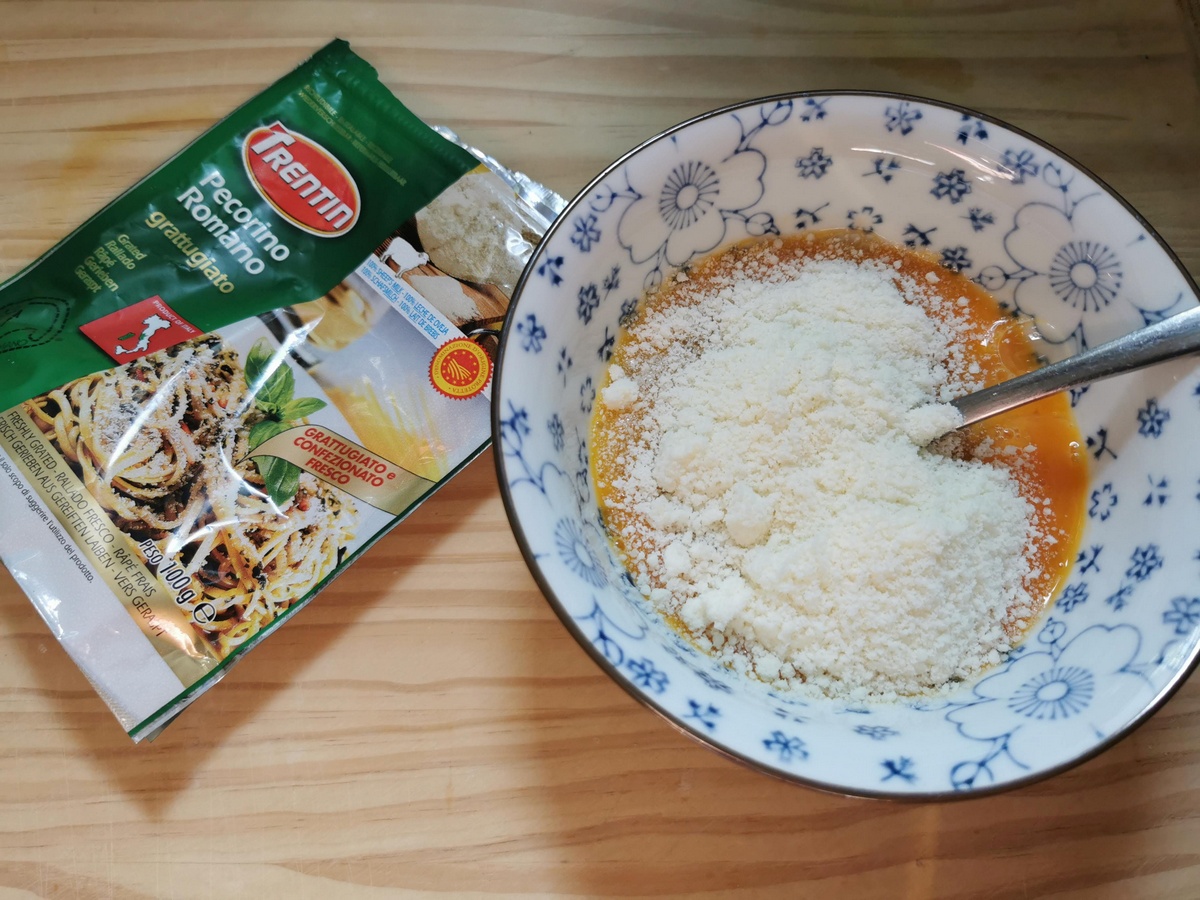 Beaten eggs in small bowl with grated pecorino on top.