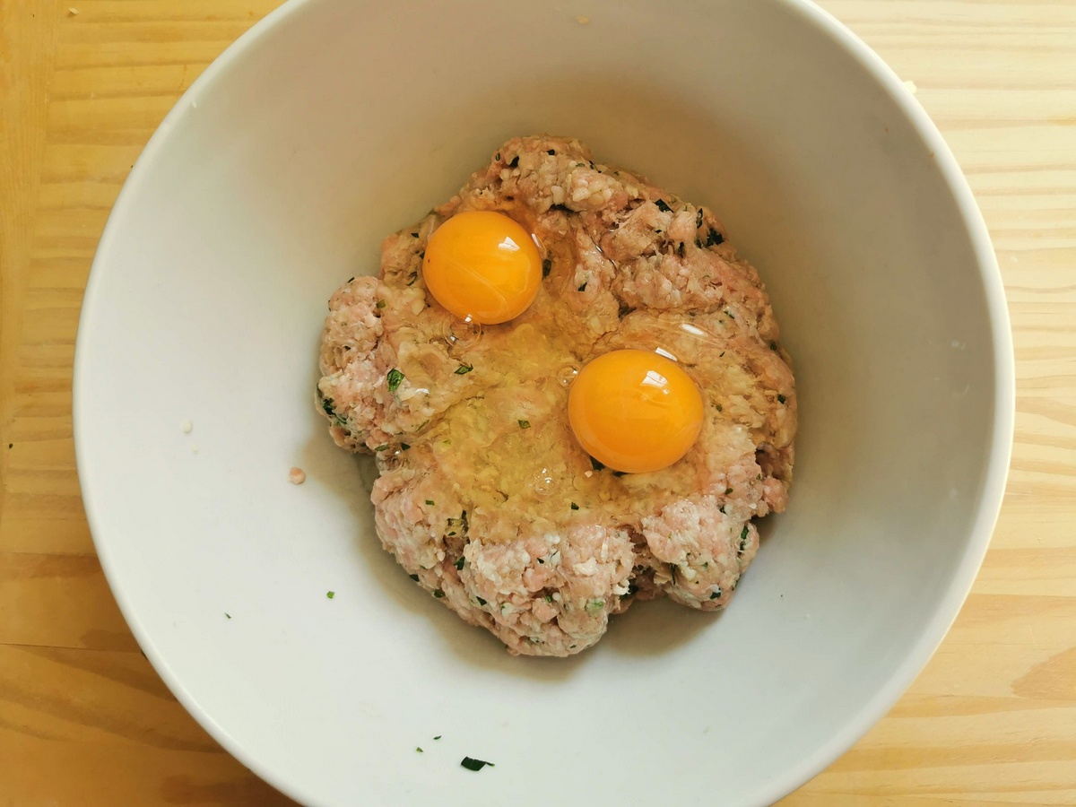 2 eggs broken into ground veal mixture in large bowl.