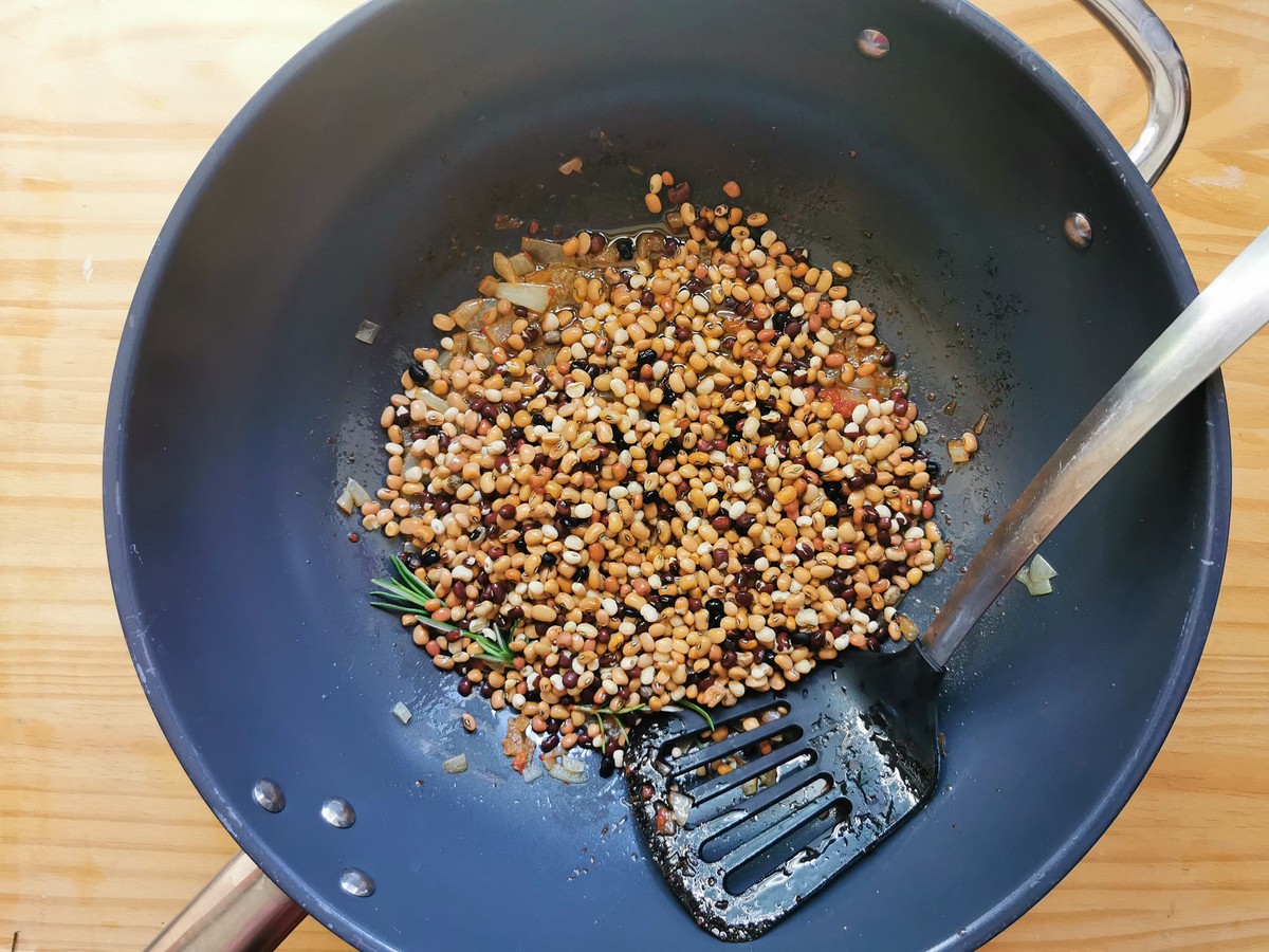 Uncooked Trasimeno beans in deep frying pan with onions, tomato paste and rosemary