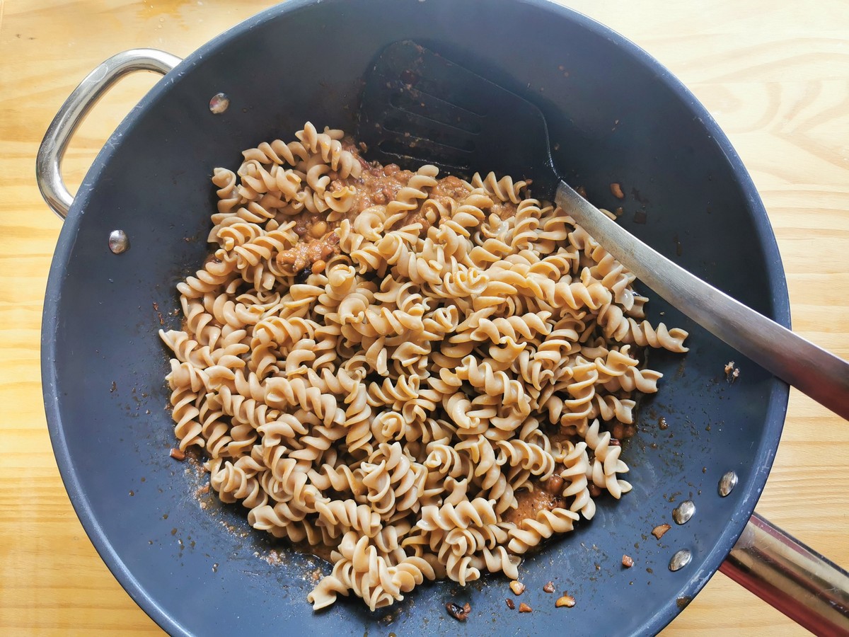 Cooked high protein pasta on top of bean sauce in deep frying pan.