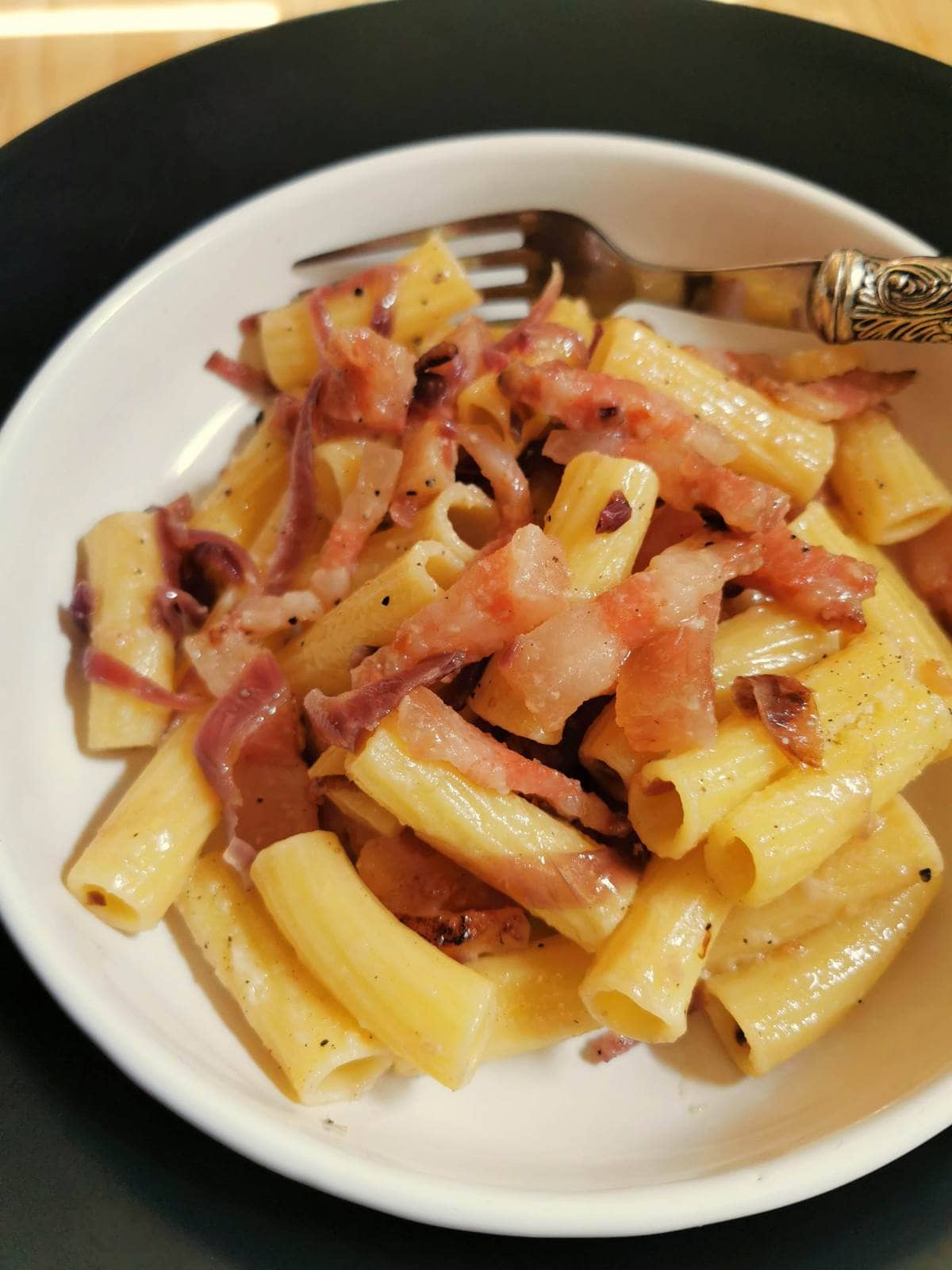 Easy red onion pasta with guanciale or pancetta in white bowl.