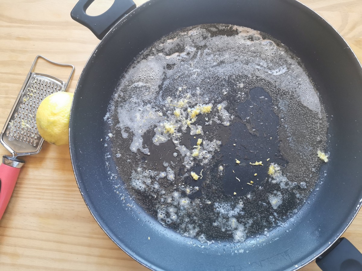 Melted butter inlarge skillet with grated lemon zest on top.