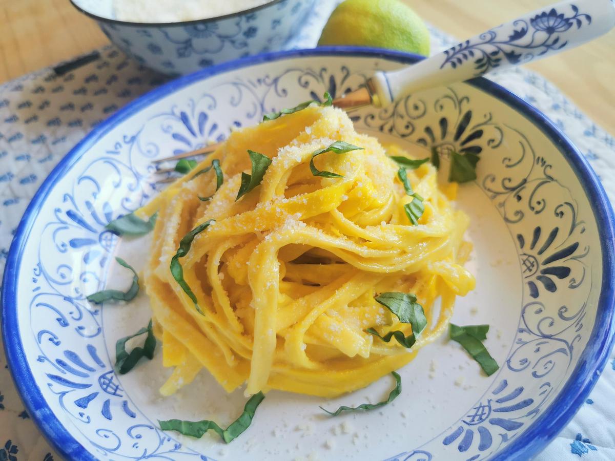 Easy saffron, lemon and butter pasta in blue and white bowl with fresh basil sprinkled on top.