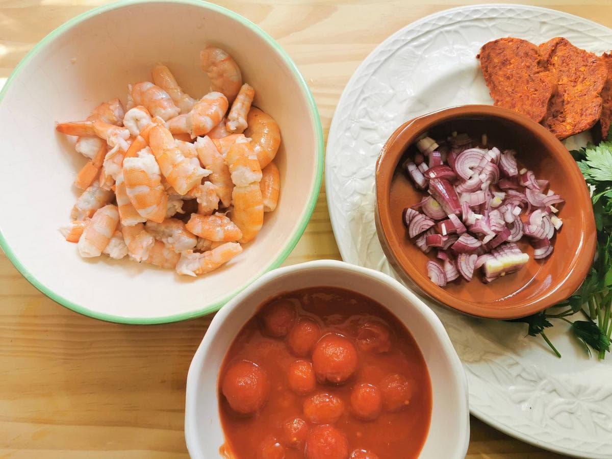 Prepared ingredients for pasta with nduja sauce and shrimp: cleaned shrimp and peeled and sliced onion in bowls.