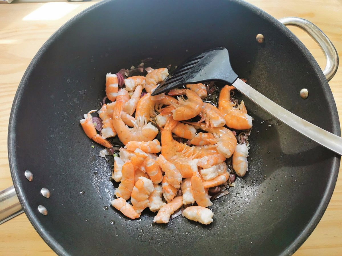 Shrimp cooking in skillet with onion.