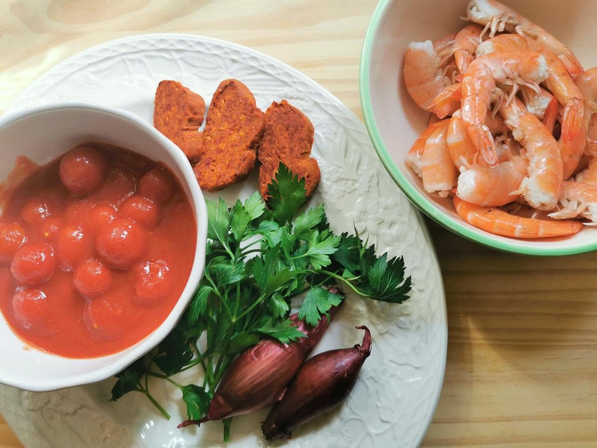 Ingredients for nduja sauce with shrimp: canned cherry tomatoes, red onions, fresh parsley, sliced nduja sausage and shrimp tails.