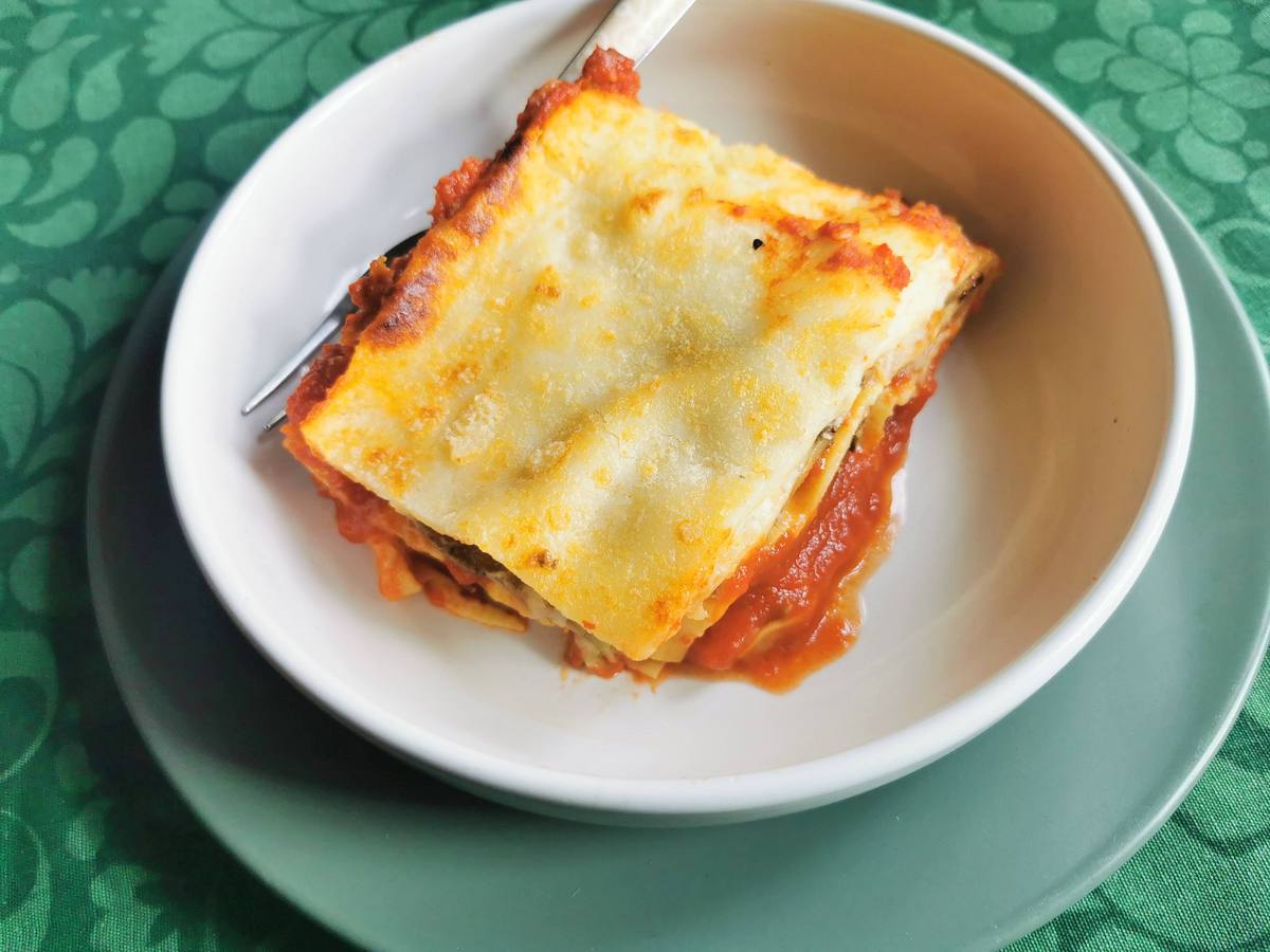 Portion of eggplant parmigiana lasagna in white bowl.