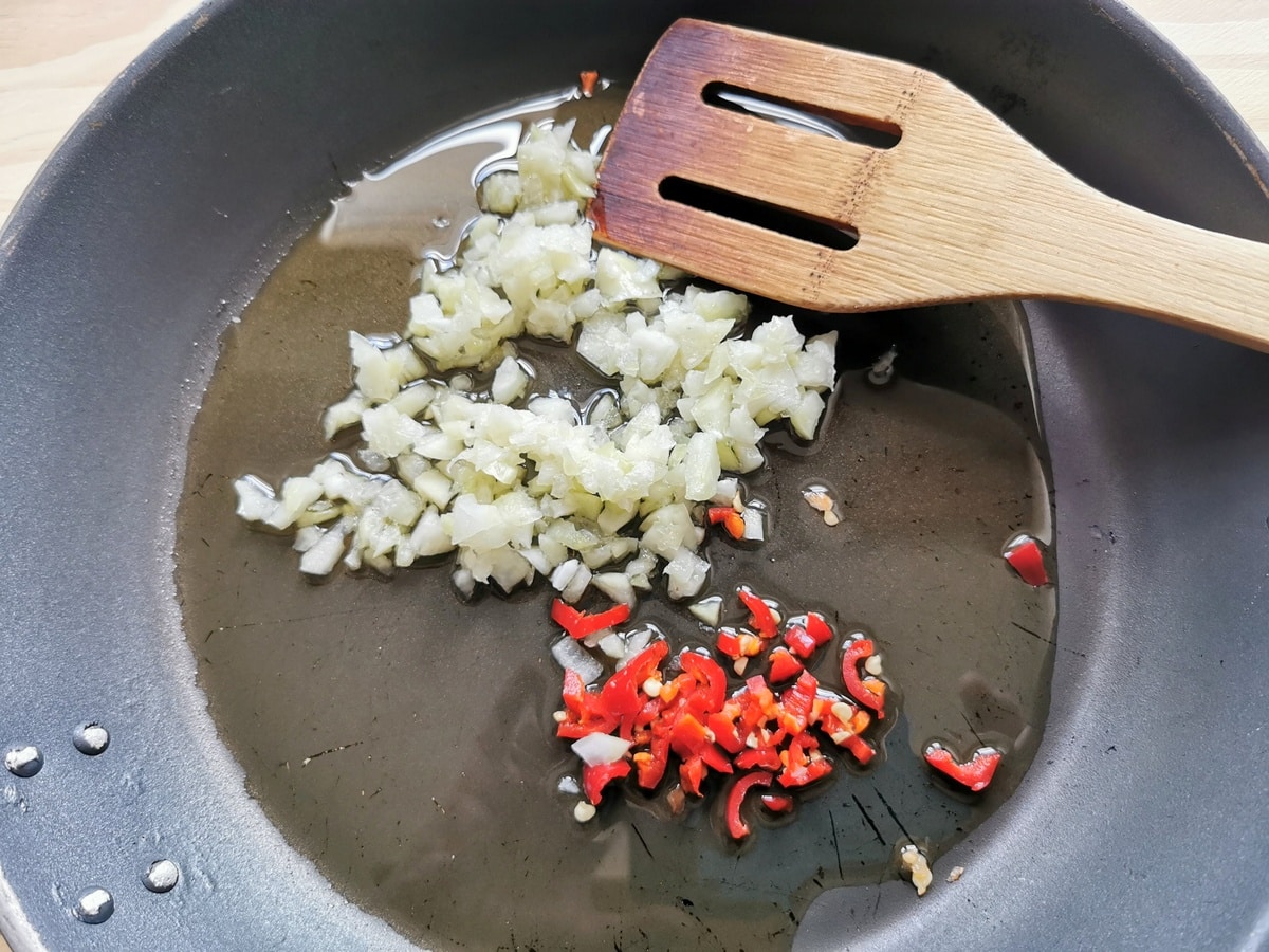 Chopped aglione (elephant garlic) and peperoncino in skillet with olive oil.