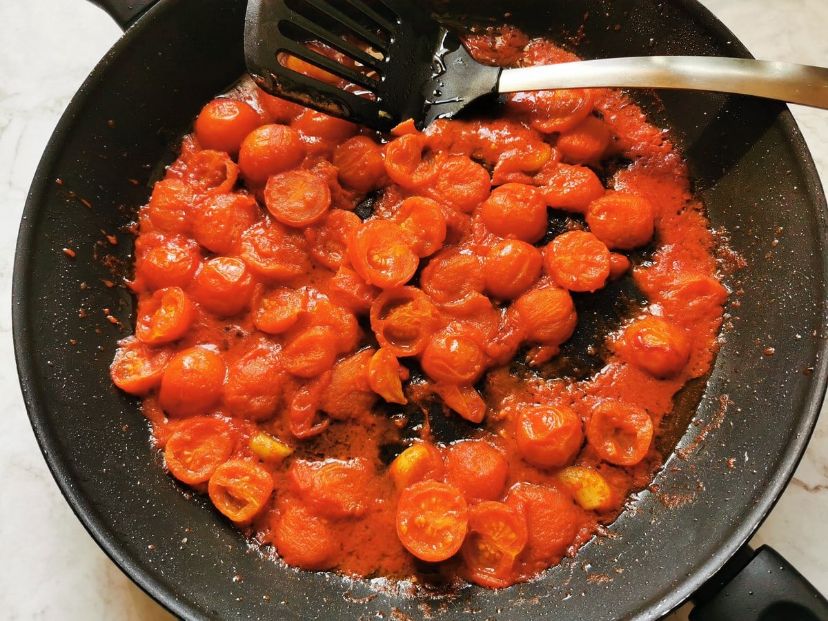 Cherry tomatoes being cooked in a saute pan.