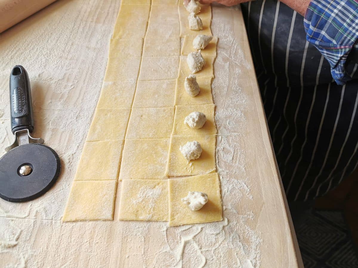 Piping the filling onto the cut pasta dough.