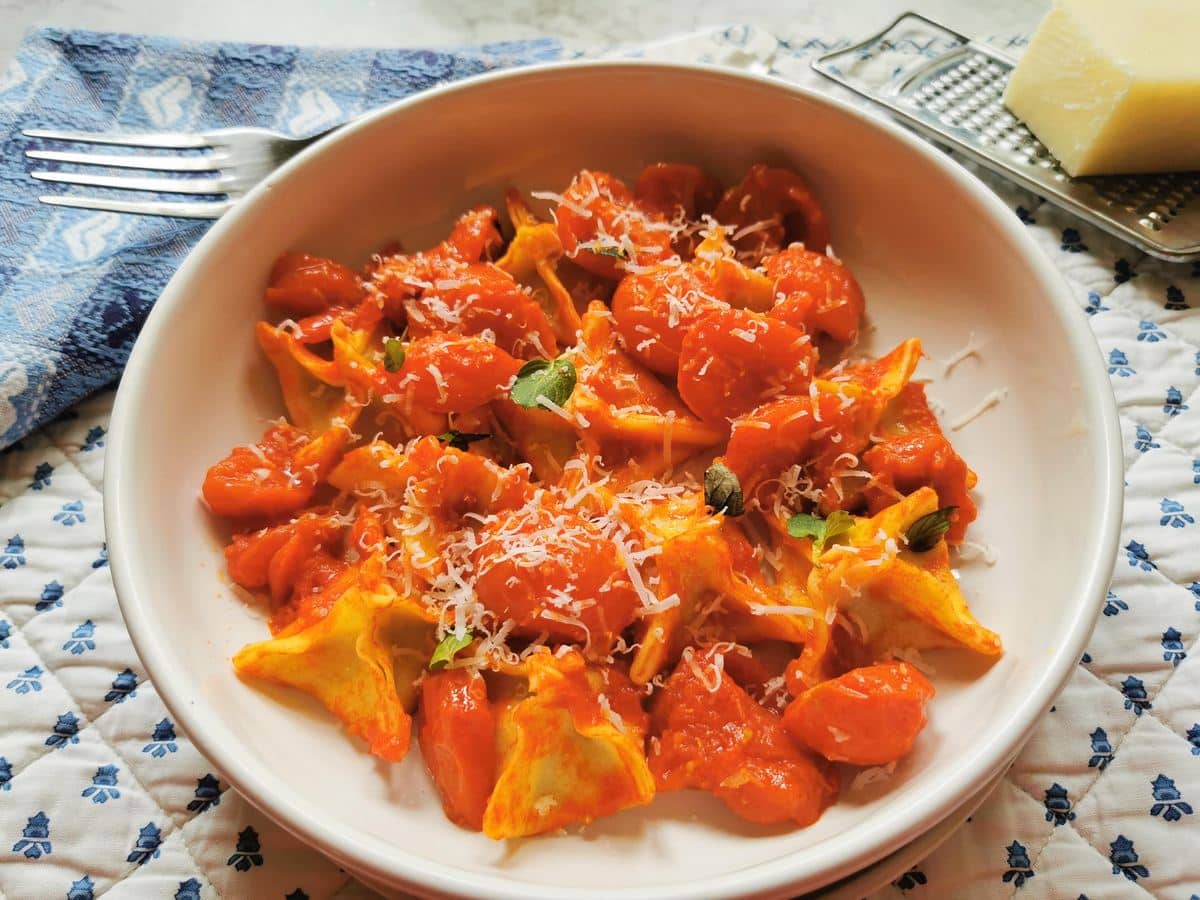 Fagottini in a cherry tomato sauce being served on a table.