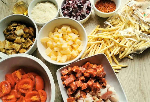 chopped onions, cheese, guanciale, porcini and tomatoes in white bowls