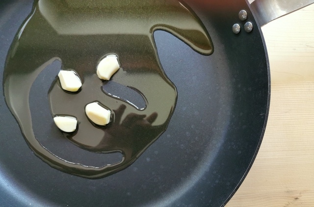 peeled garlic cloves with olive oil in skillet