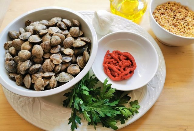 ingredients for fregola with clams on white plate