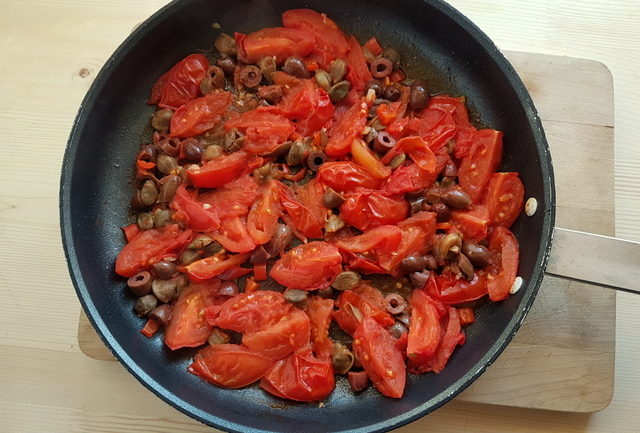 chopped tomatoes, olives and capers in frying pan