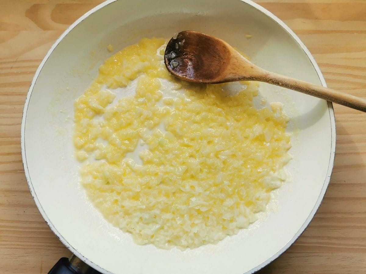 peeled and finely chopped onion frying in butter in small frying pan.