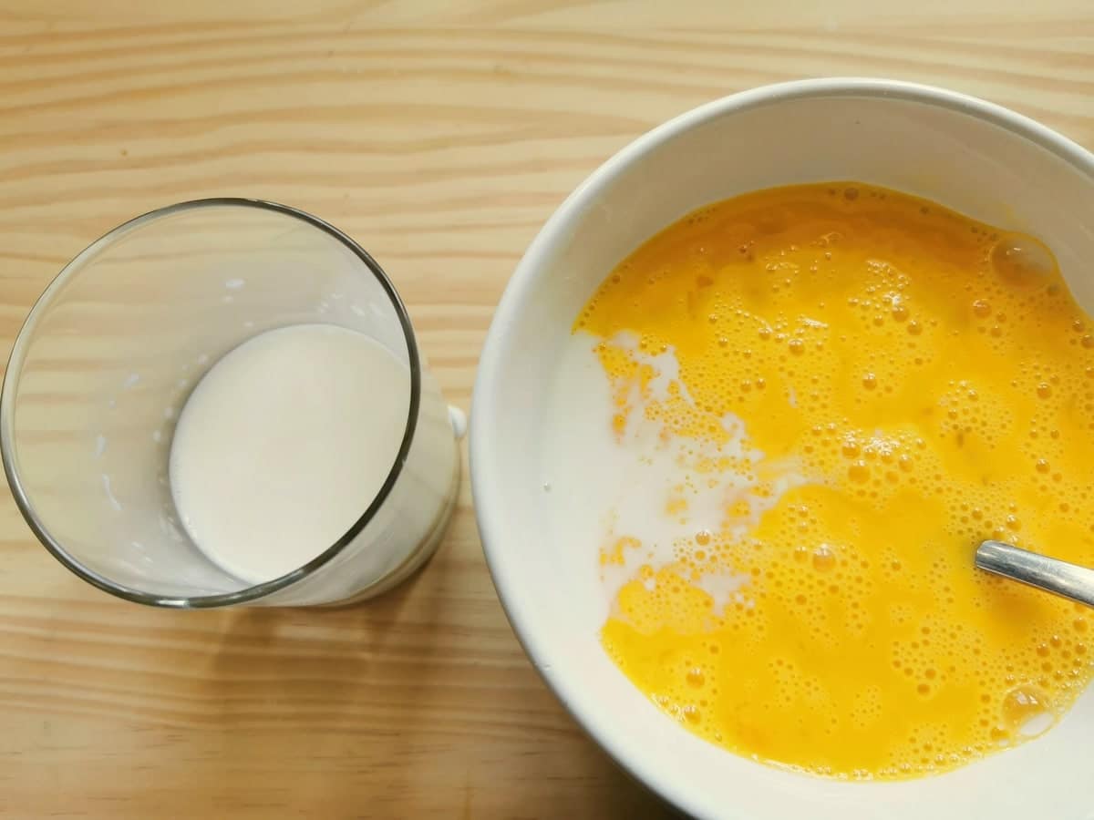 Fresh milk and beaten eggs in white bowl.