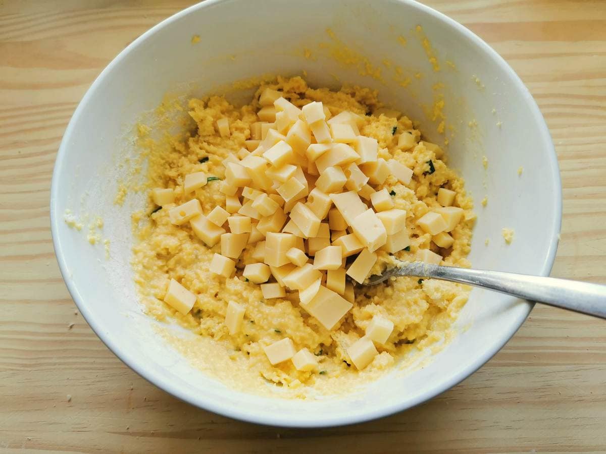 Cubes of fontina cheese in white bowl with canederli mixture.