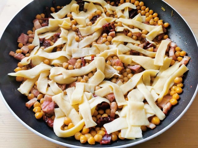 homemade sagne pasta with chickpeas and pancetta in skillet