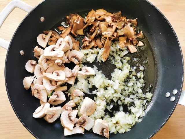 chopped porcini, champignons and onion cooking in skillet