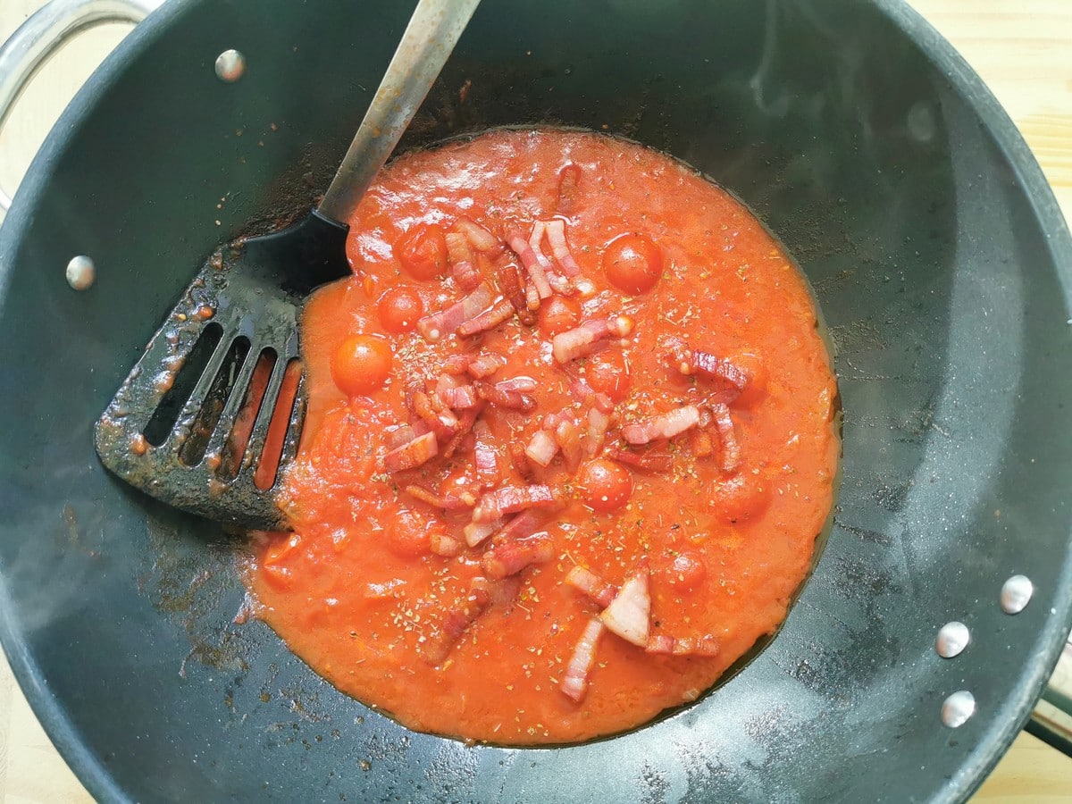 Cooked pancetta and dried marjoram added to the pancetta and tomato sauce in large skillet.