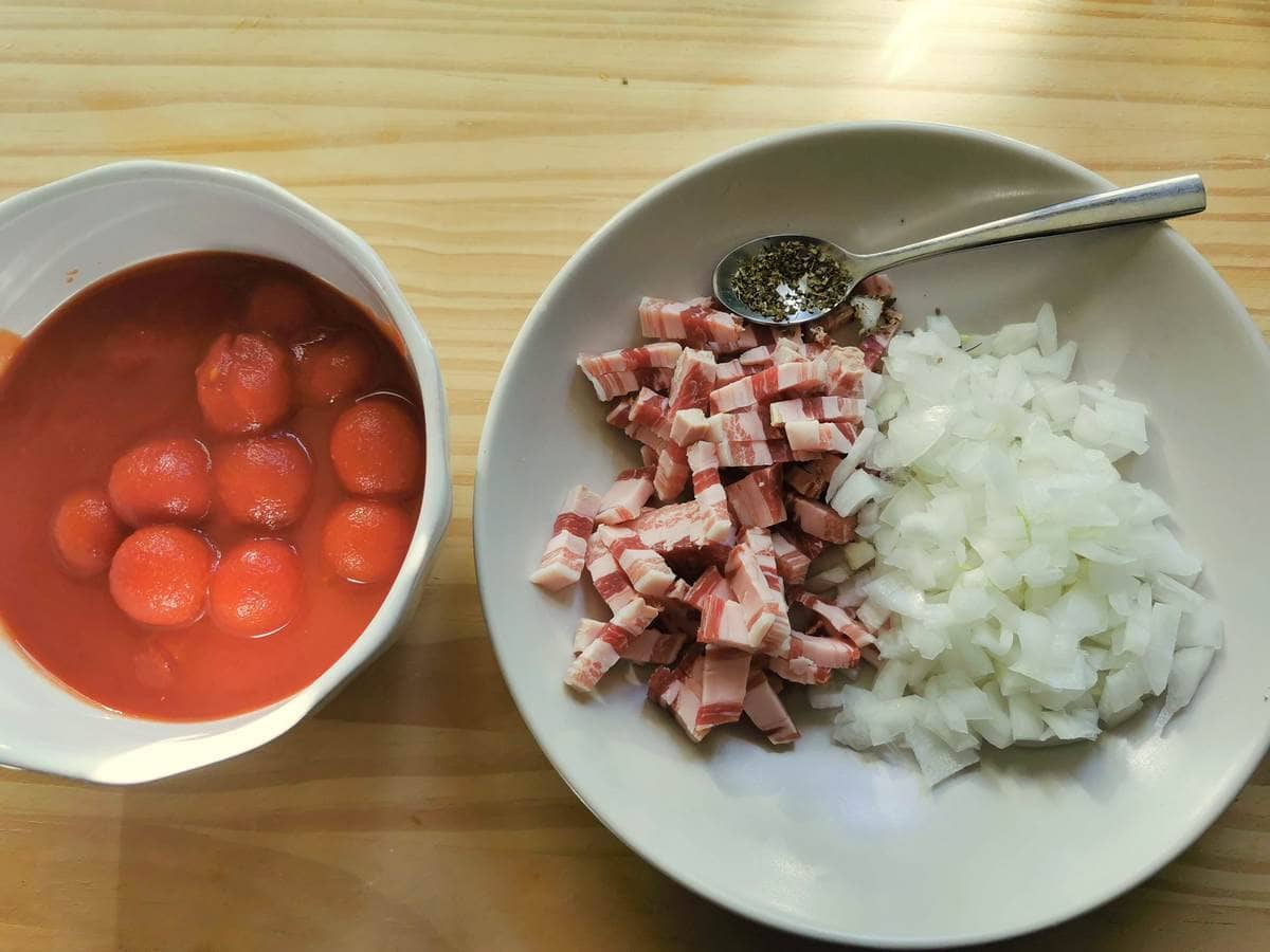 Diced pancetta and chopped onion on white plate and canned cherry tomatoes in white bowl.